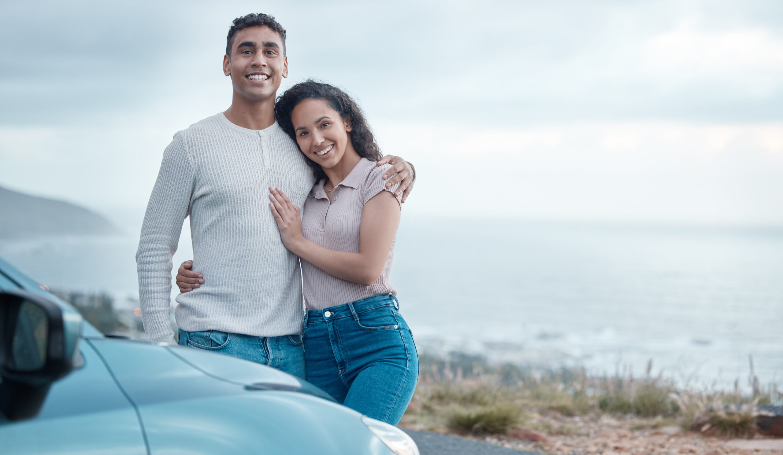 Young man and woman standing next to car