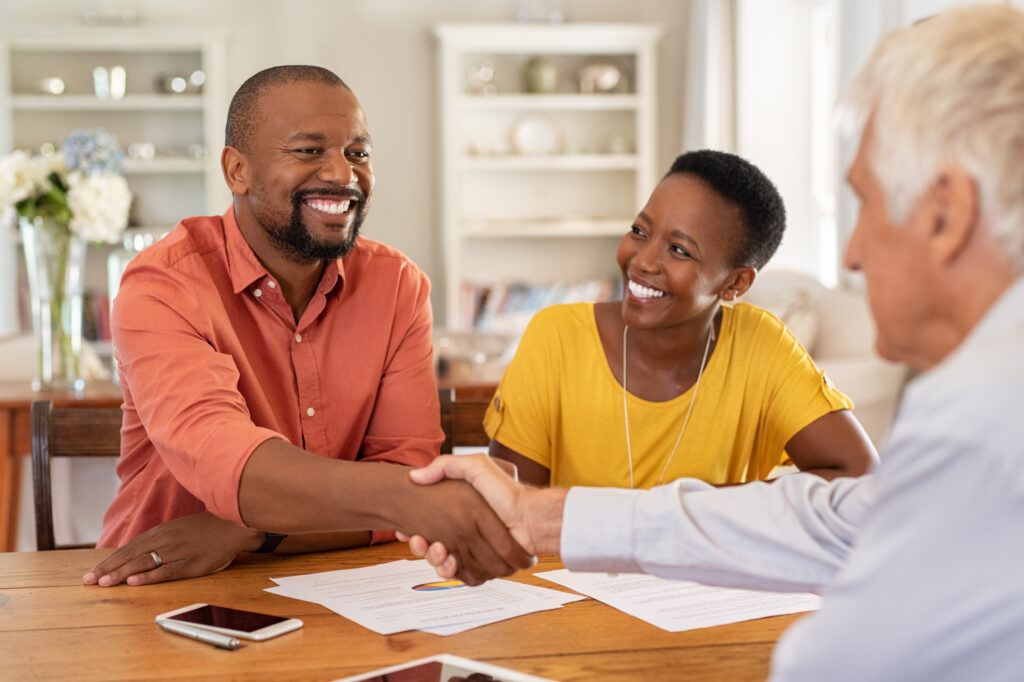 Insurance agent shaking hands with young couple.