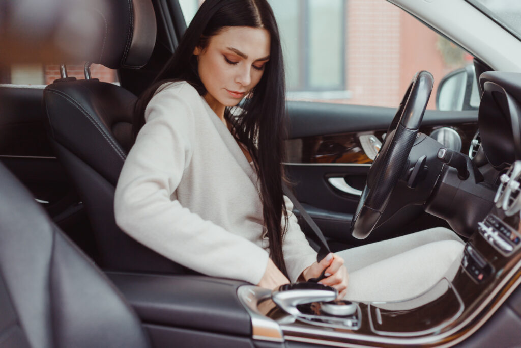 Woman buckling her seatbelt before driving.