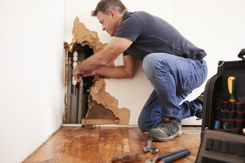 Handyman repairing a burst water pipe and water damage.