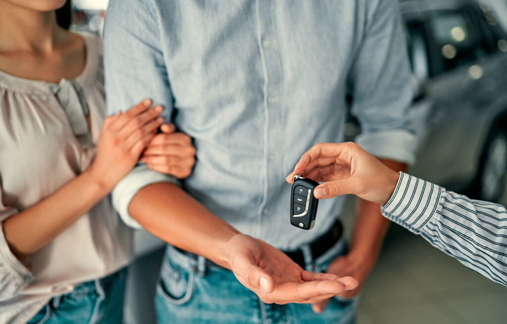 Car salesman handing new car keys to owners