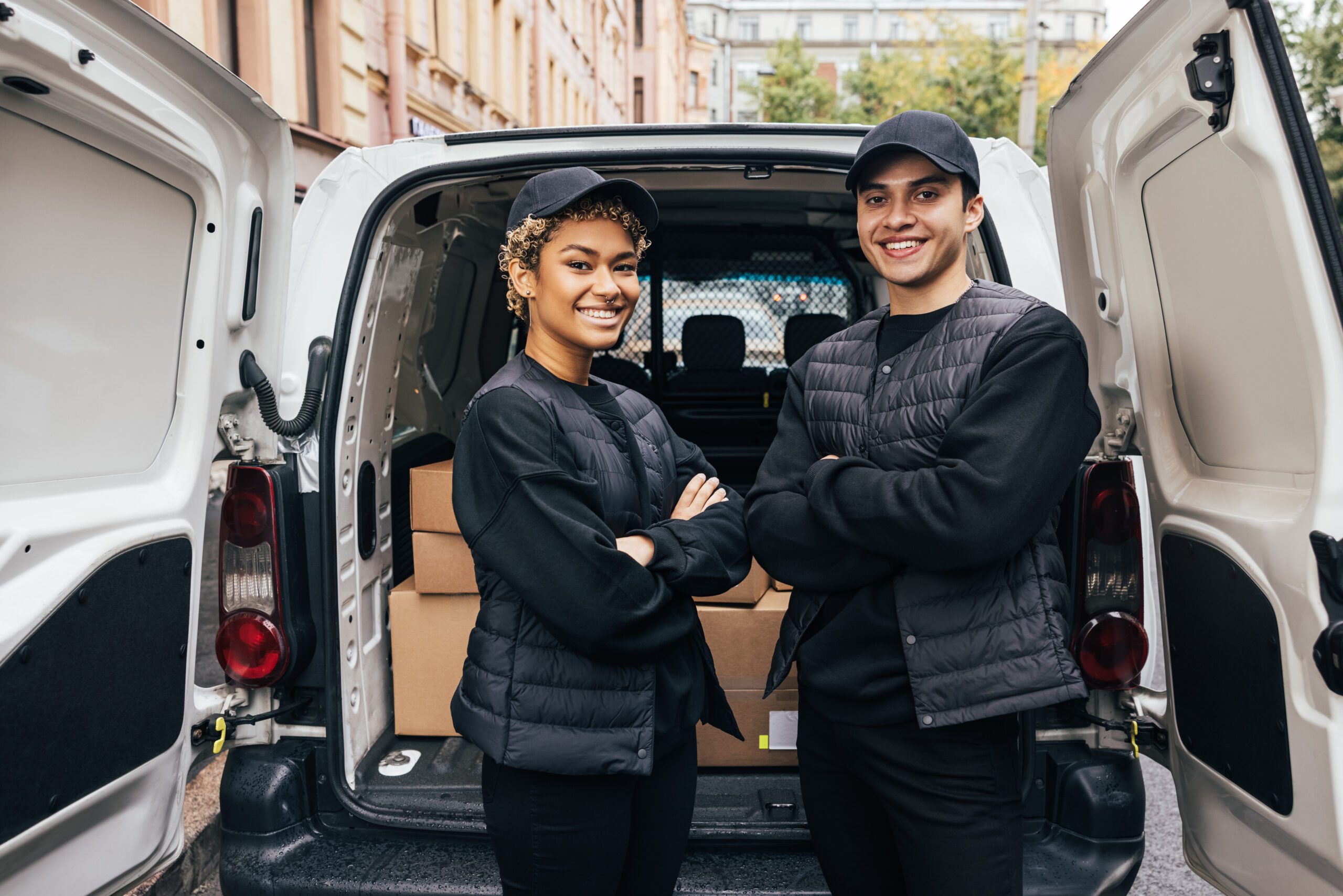 Male and female delivery driver standing in front of open delivery van