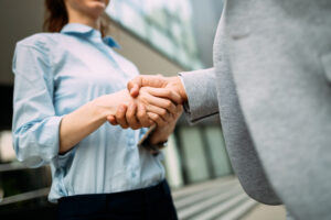 Close-up picture of businesswoman and businessman shaking hands outside company