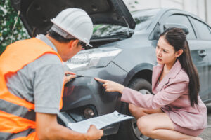 insurance adjuster inspecting damaged car with woman