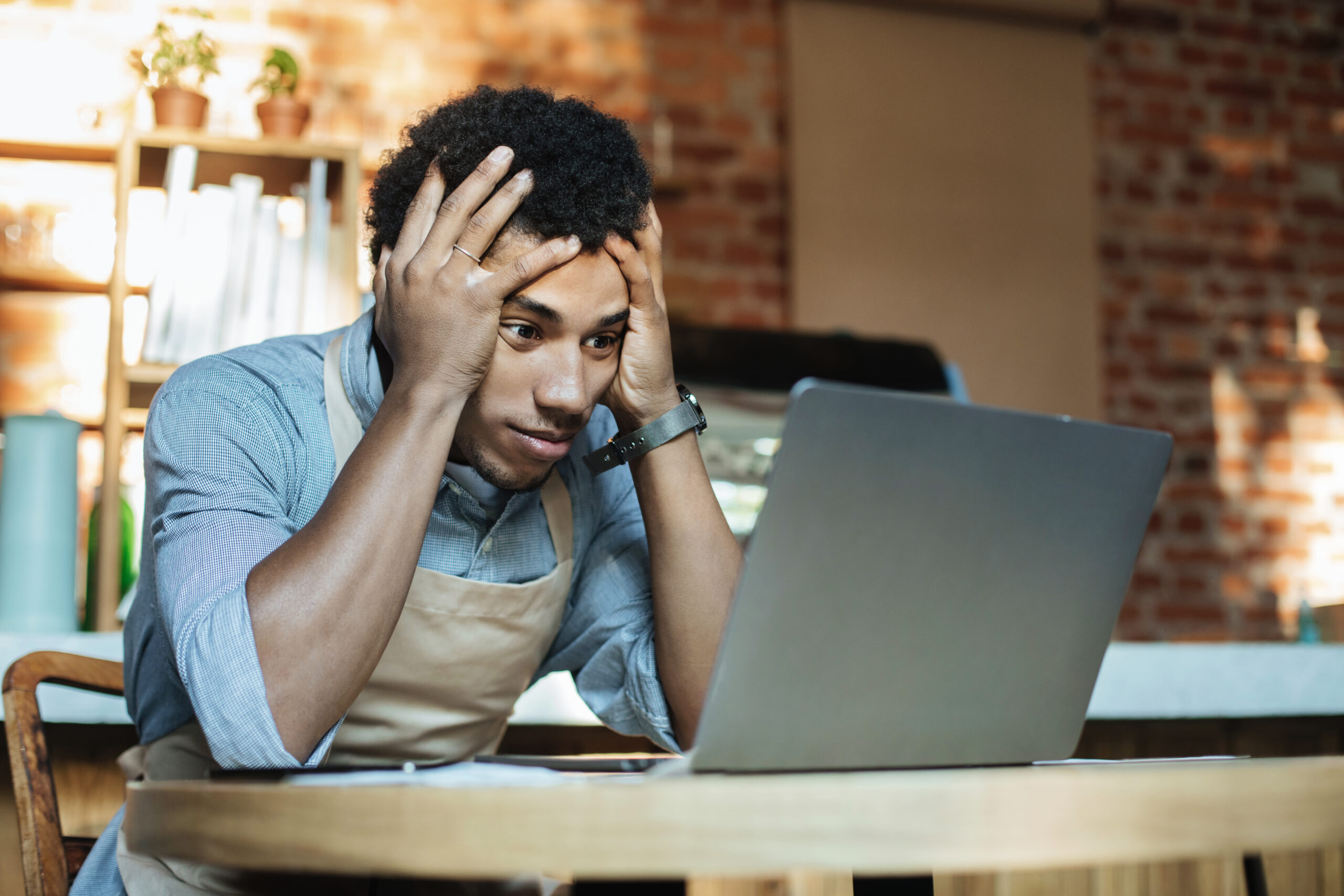 worried business owner looking at laptop