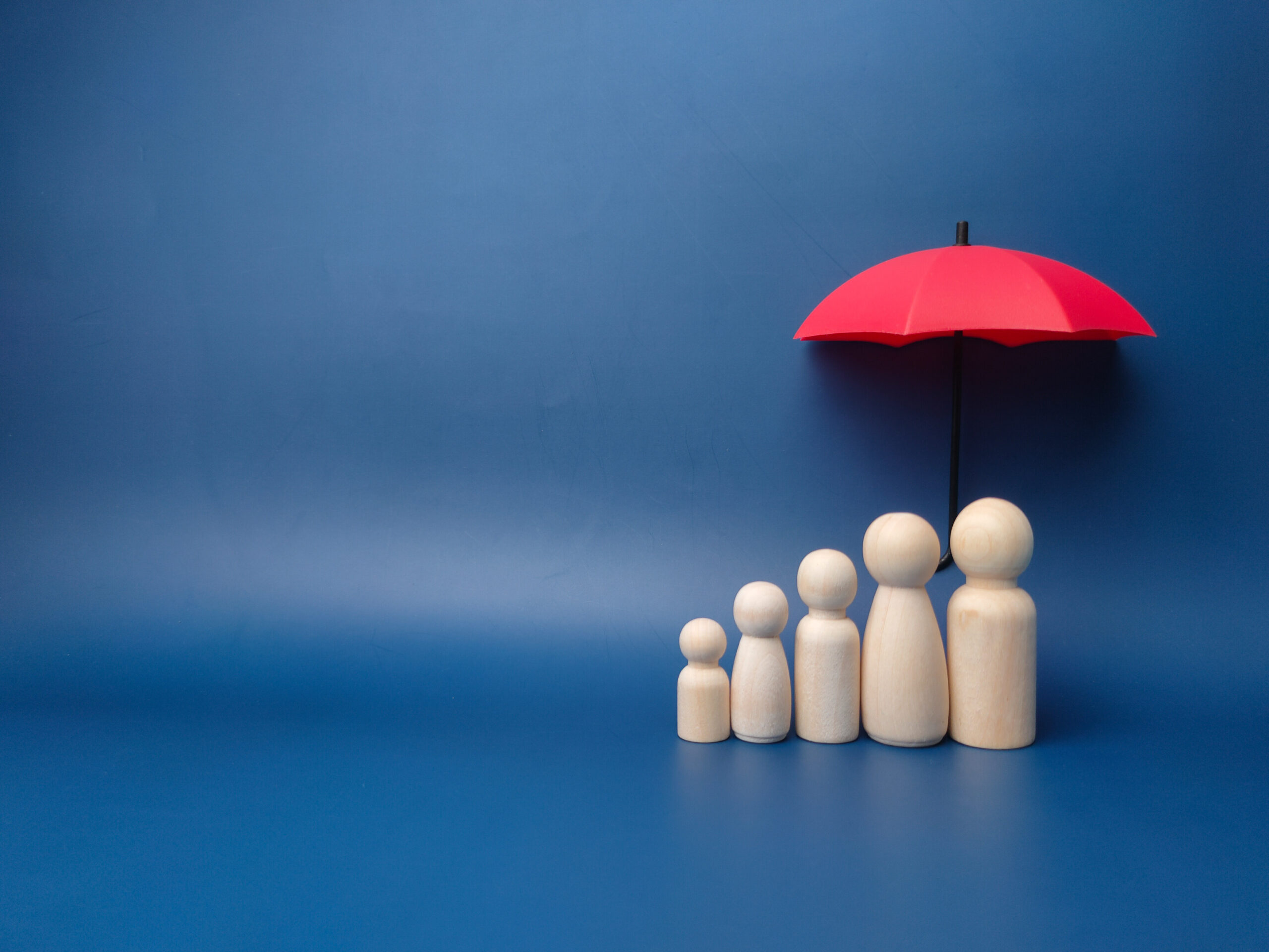 Family of peg dolls under red umbrella