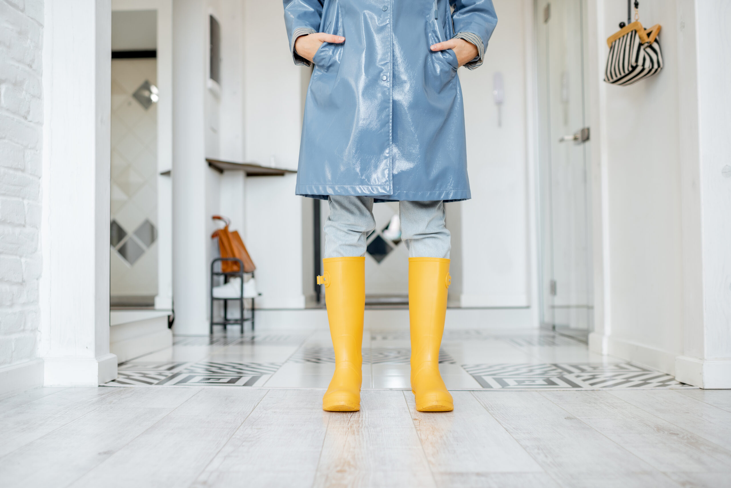 Woman wearing raincoat and yellow rainboots indoors